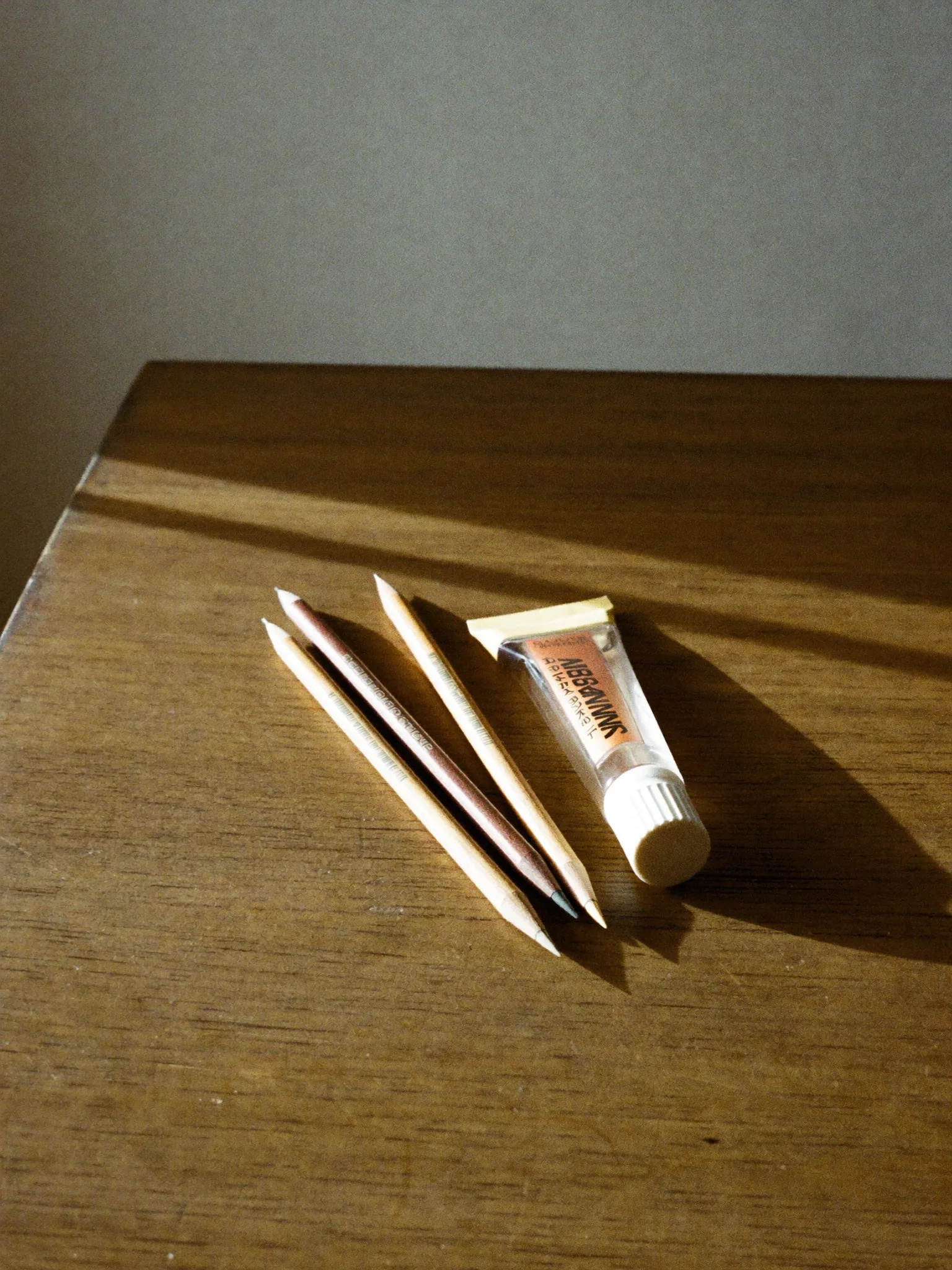 Three wooden brow pencils fanned out beside a clear brow gel.